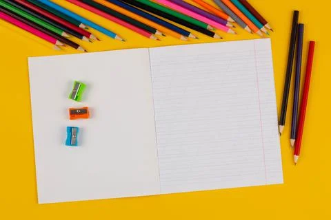School notebook on a yellow background with copy space text, colorful pencils Stock Photos