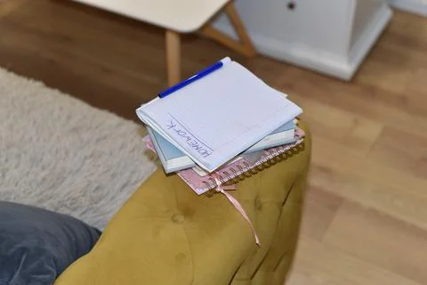 School notebooks with HOMEWORK text and blue pen on yellow upholstered furniture Foto stock