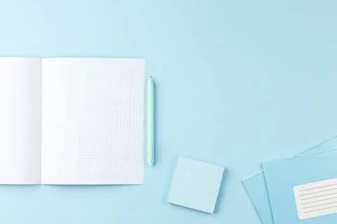 School notepad with study supplies on blue desk. Stock Photos