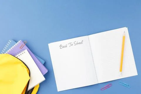 School notepad with study supplies on blue desk. Stock Photos