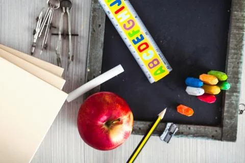 School objects for students. Chalkboard, pencils, crayons and apple Stock Photos