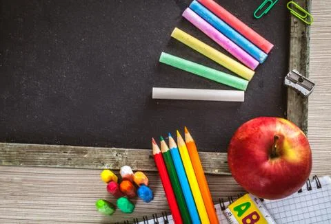 School objects for students. Chalkboard, pencils, crayons and apple Stock Photos