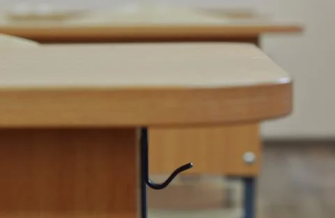 School office. hook for a school bag, a backpack on a desk close-up on a blur Stock Photos