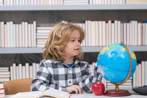 School pupil looking at globe in library, geography lesson. School and kids Stock Photos