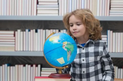 School pupil looking at globe in library, geography lesson. School and kids Stock Photos