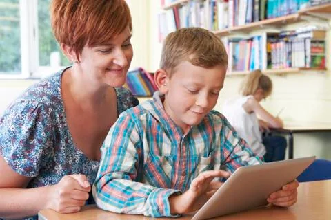 School pupil with teacher using digital tablet in classroom Stock Photos