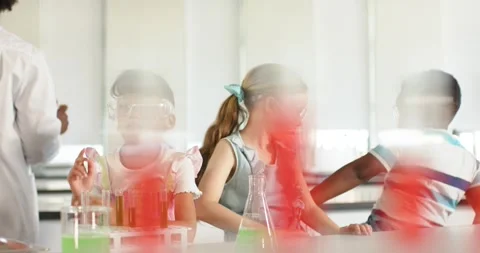 School pupils fixing goggles, using test tubes, flask as teacher in lab coat Stock Footage 335927818