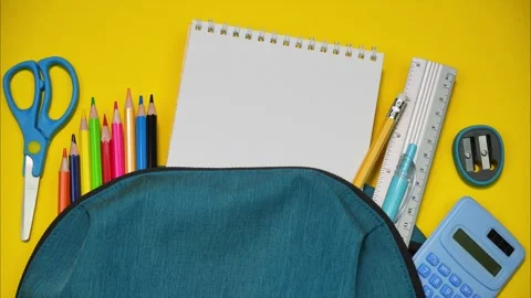 School stationery moving out of backpack on yellow background. Stop motion Stock Footage 284562609