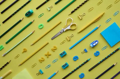School stationery products in diagonal pattern on yellow background, flatlay. Stock Photos