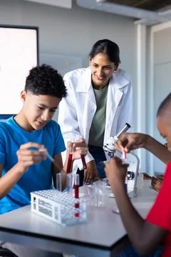 In school, students conducting science experiment with test tubes and microscope Foto stock