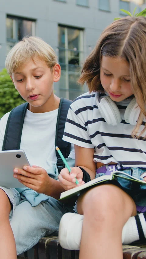 School students friends outdoors using digital tablet computer . Kids sitting on Stock Footage 331588076