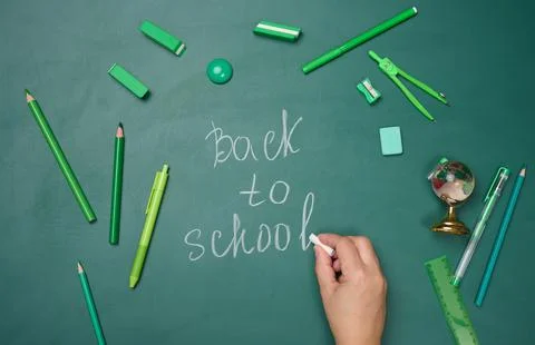 School supplies on empty green chalk board, top view. Stock Photos