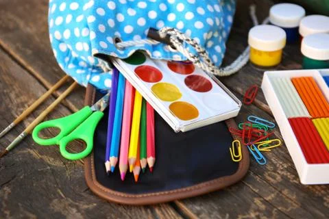 School supplies fall out of backpack on old wooden background. Stock Photos