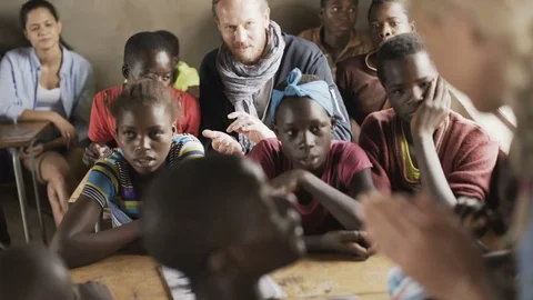 School teacher &amp; charity workers in class with children from African community Vidéo 77409868