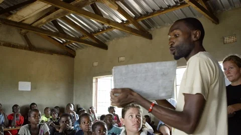 	School teacher &amp; charity workers in class with children from African community Stock Footage 77419588