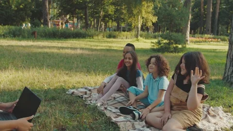 School teacher using laptop, showing study material to pupils outdoors Video stock 158911259