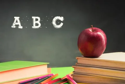 A school teacher's desk with a stack of exercise books colored pencils and gr Stock Photos