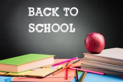 A school teacher's desk with a stack of exercise books colored pencils and gr Stock Photos