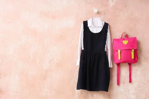 School uniform and pink backpack hanging on wall, back to school preparation, Stock Photos