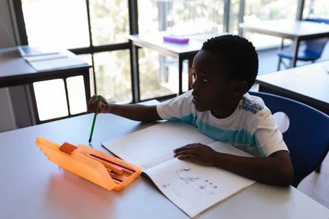 In school, young boy drawing in notebook, concentrating on creative work, c.. Stock Photos