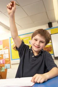 Schoolboy Answering Question In Classroom Stock Photos