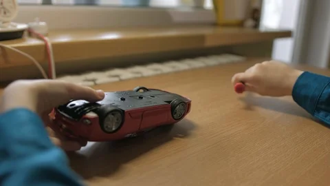 Schoolboy assembling his red model car. Used screwdriver to screw cogs Stock Footage 129402565