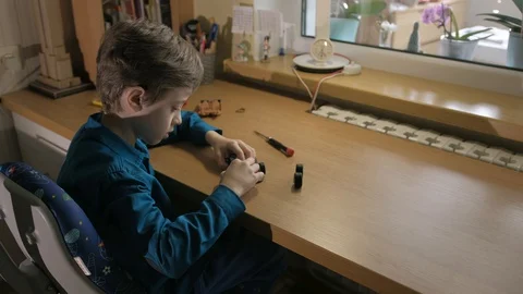 Schoolboy assembling his red model car. Used screwdriver to screw cogs Stock Footage 129402937