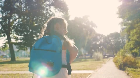A schoolboy with a backpack and a book in the Park. A happy girl runs to school Stock Footage 138294444