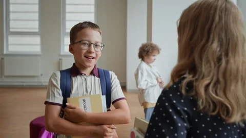 Schoolboy with Backpack Holding Book Talking to Classmate in School Stock Footage 345822745