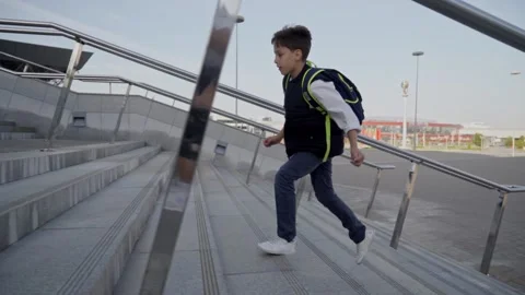 Schoolboy with backpack run upstairs to school for lessons at sunny day. Side Stock Footage 140082505
