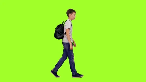 Schoolboy with backpack walking on green chroma key background Stock Footage