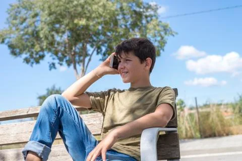 Schoolboy on bench taking break using mobile Stock-Fotos