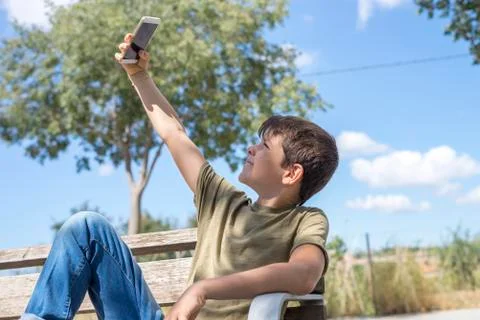 Schoolboy on bench taking break using mobile Stock Photos