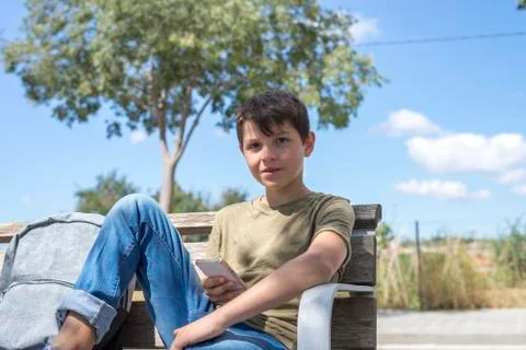 Schoolboy on bench taking break using mobile Stock Photos