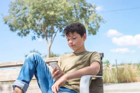 Schoolboy on bench taking break using mobile Stock Photos