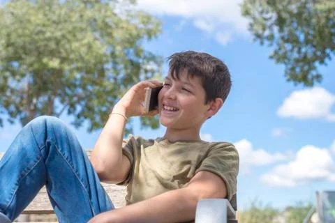Schoolboy on bench taking break using mobile Stock Photos
