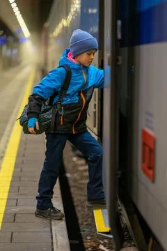 A schoolboy in a blue jacket and hat with a backpack enters a train carriage 写真素材