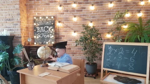 A schoolboy - a boy in a graduate cap studies the globe with a magnifying glass Stock Footage 169048015