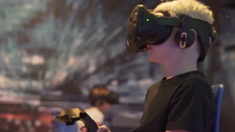 A schoolboy boy plays augmented reality in 3D glasses in a computer game club Stock Footage 142365193