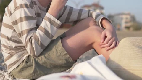 A schoolboy boy without a face eats a banana in a city park in the summer Stock Footage 234646875