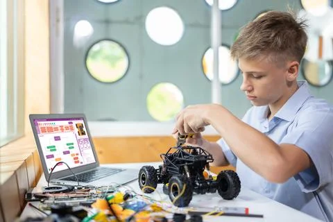 Schoolboy carefully using pliers fixing robotics car in STEM class. Edification. 스톡 사진