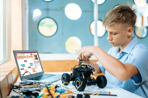 Schoolboy carefully using pliers fixing robotics car in STEM class. Edification. Stock Photos