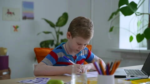 Schoolboy doing homework and sitting at table with laptop in apartment room Stock Footage 155269418