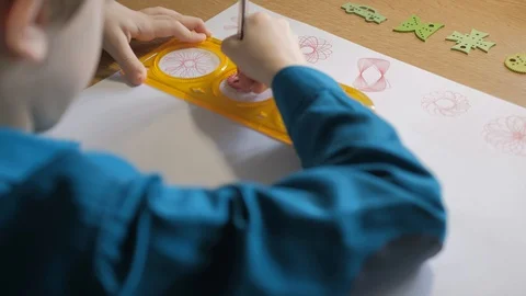 Schoolboy draws with red pen patterns, using the graphical ruler Stock Footage 129402834