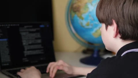 A schoolboy is enthusiastically writing code on a laptop while sitting at a.. Stock Footage 335258933