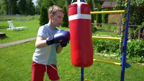 Schoolboy exercising and punching a boxing bag Stock Footage 341360438