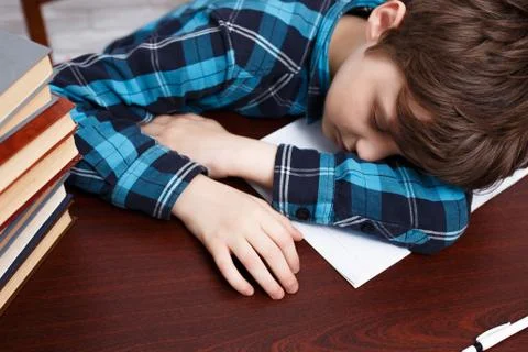 Schoolboy falling asleep while studying at copybook. School life Stock Photos