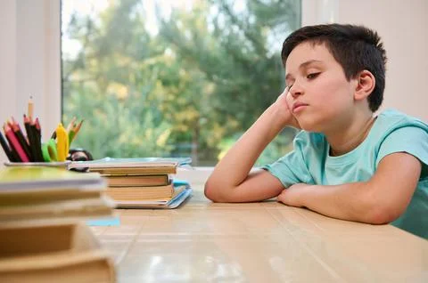 Schoolboy feeling tired while doing homework, has learning difficulties and Stock Photos