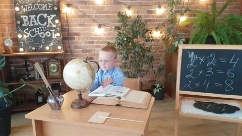 A schoolboy in glamorous glasses is studying the globe with a magnifying glass Stock Footage 169048001