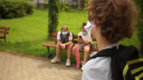 The schoolboy has put the mask on his chin and breathes while sitting on a bench Stock Footage 135831105